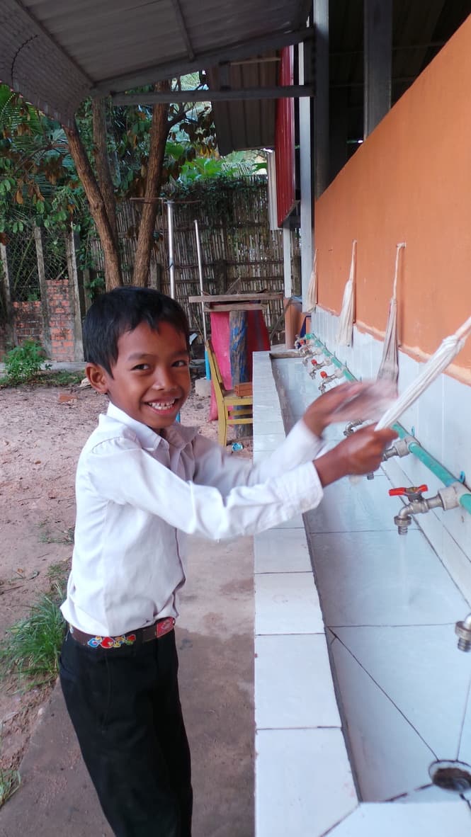 A boy at a school washing station in Cambodia