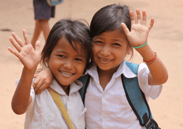 Two girls waving at school