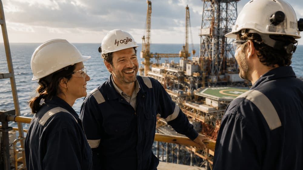 Energy specialists in hard hats reviewing project data beside an offshore rig